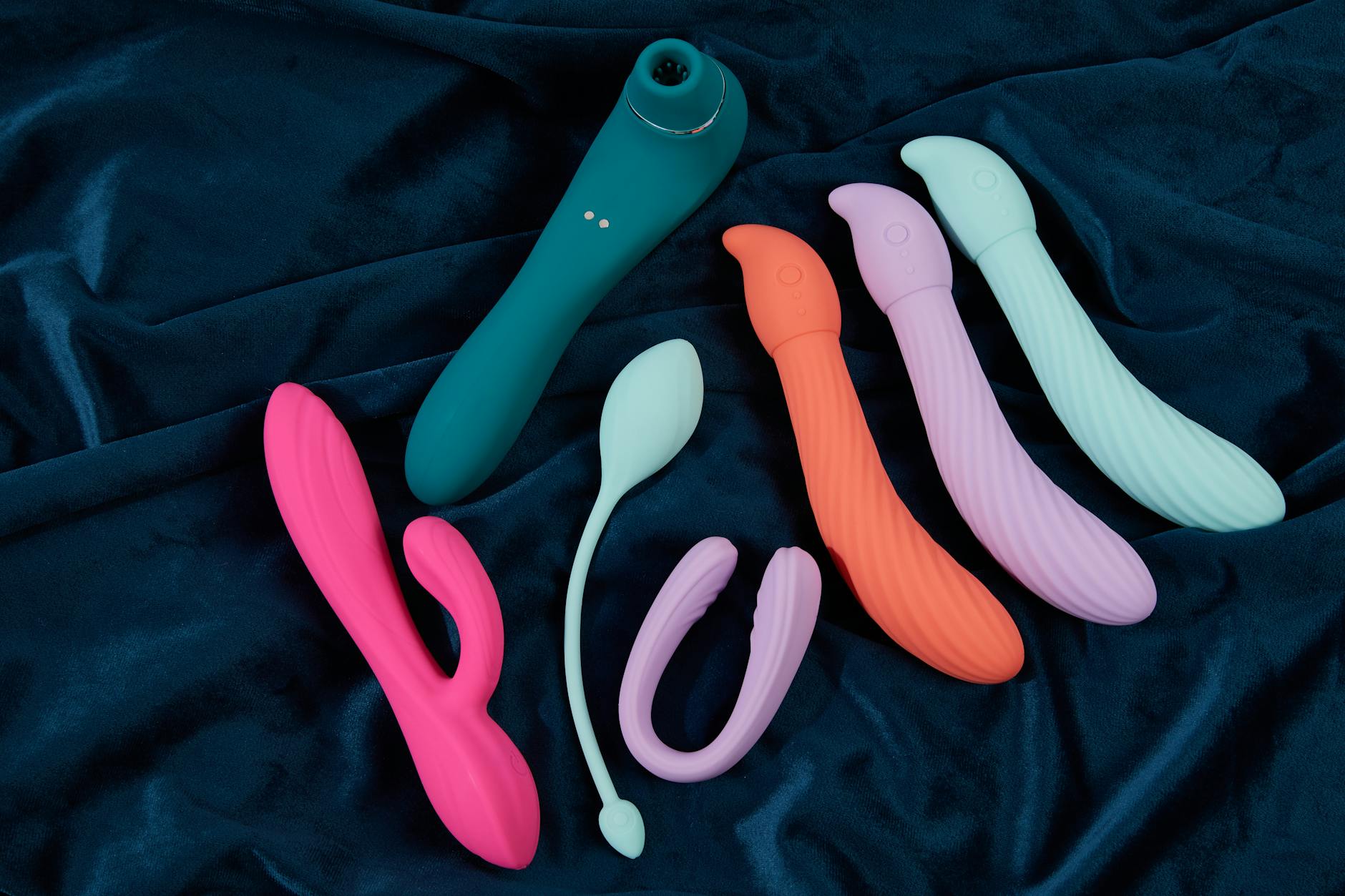 A silicone clitoral vibrator held in hand against a purple background, symbolizing intentional self-care and sexual wellness