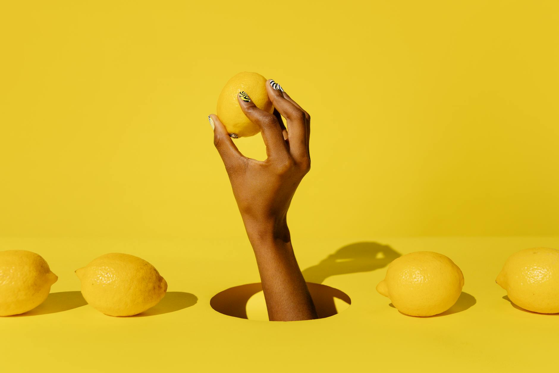 Fresh lemon held in hand against yellow background, symbolizing renewal and sensation