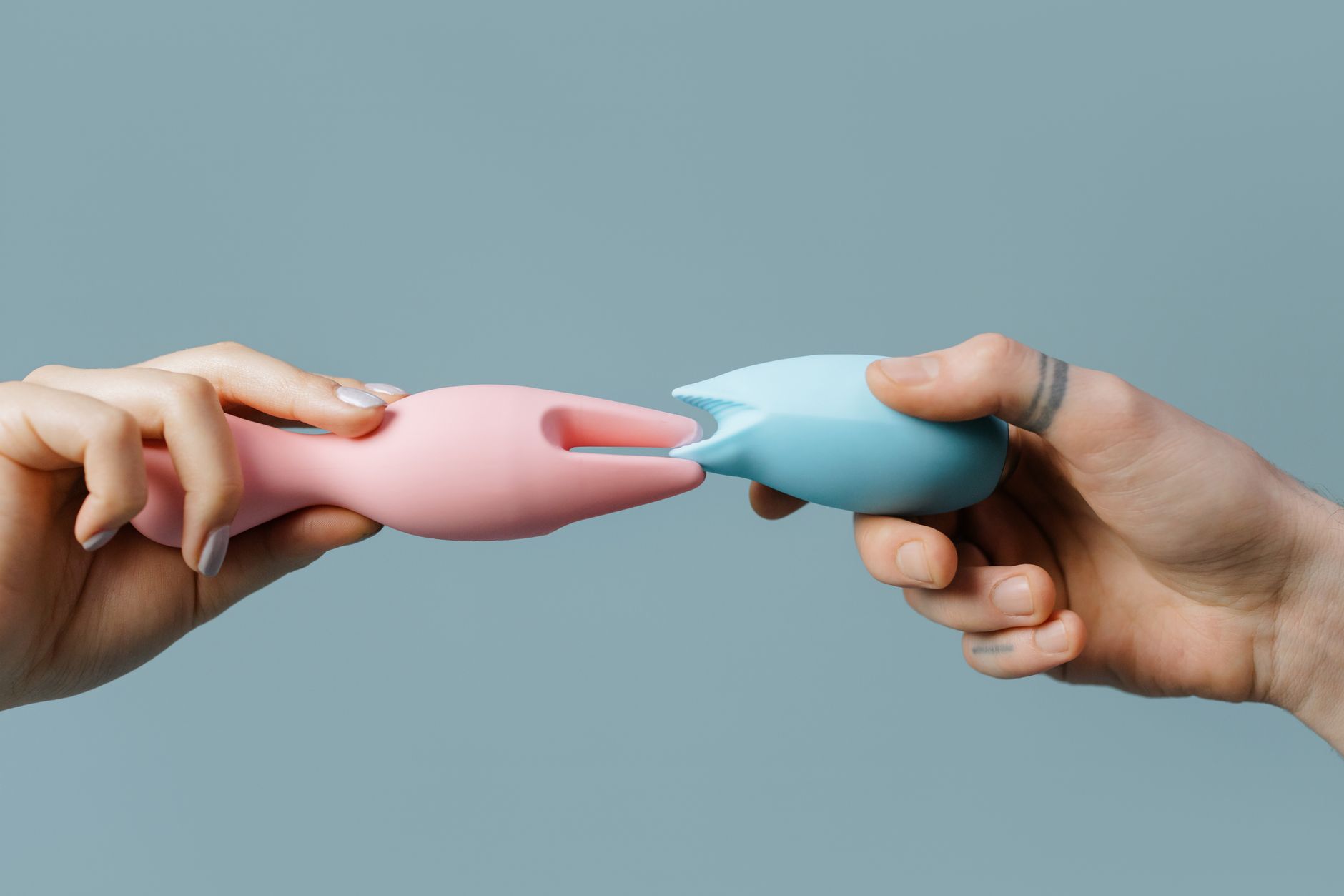 Hand holding a sleek blue vibrator against a purple background