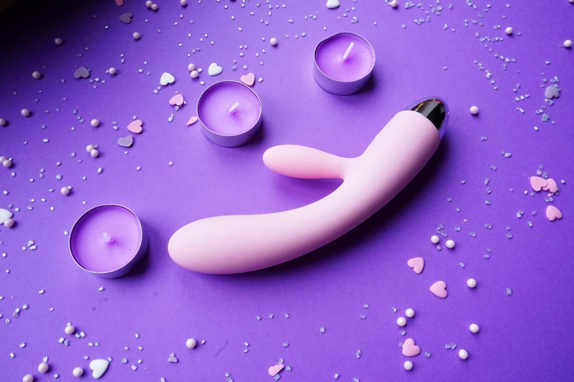 A vibrator on purple background with candles and hearts, symbolizing rekindled romance and trust