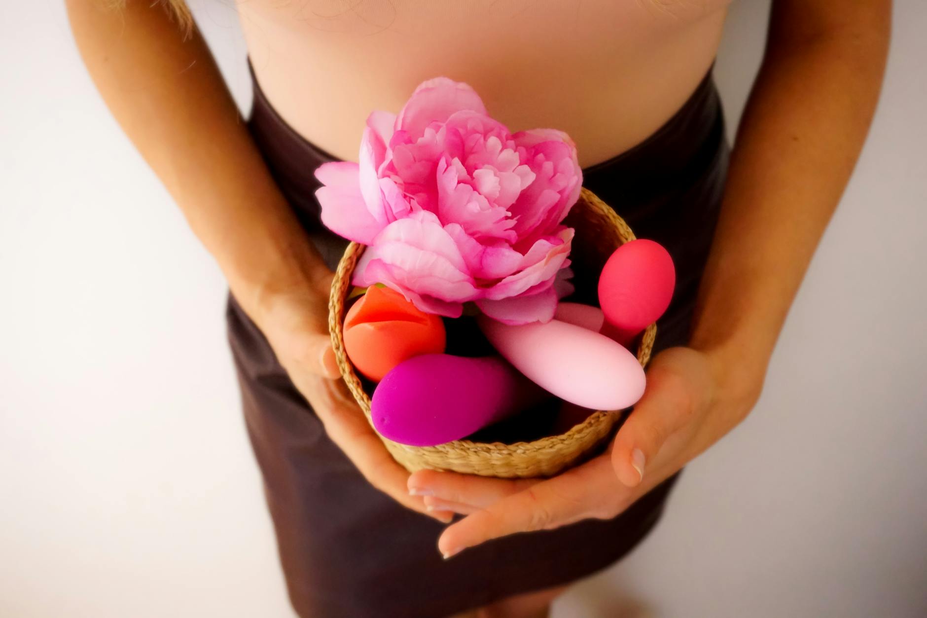 A person holding a basket containing colorful Lemon Clitoral Vibrators and flowers.